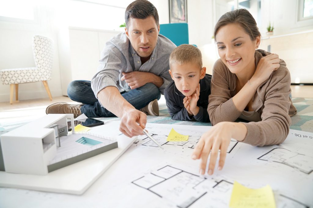 Family at home looking at future house blueprint and model